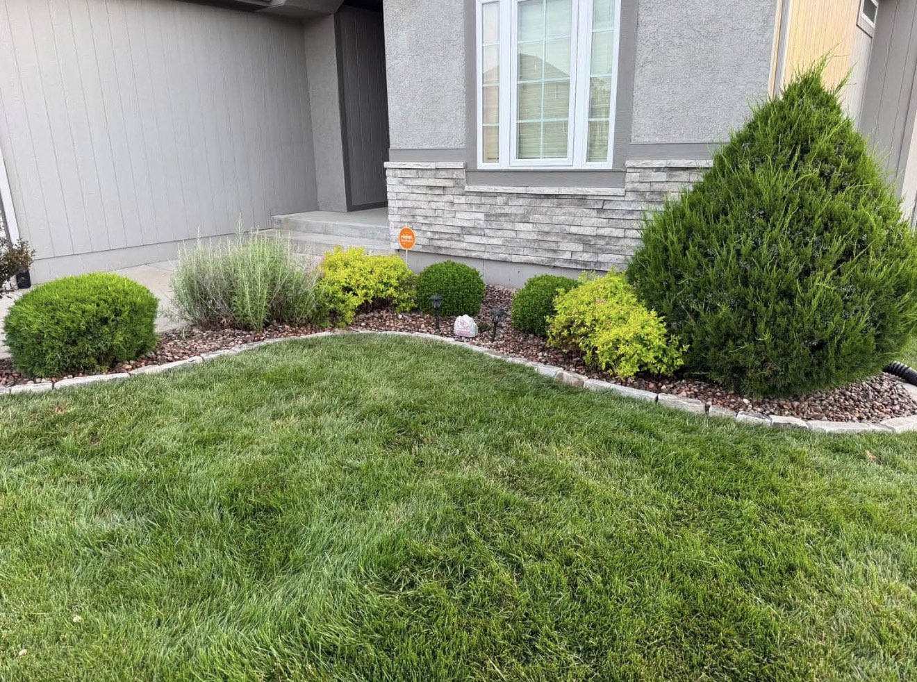 Well-maintained residential front yard with landscaped beds and healthy green lawn