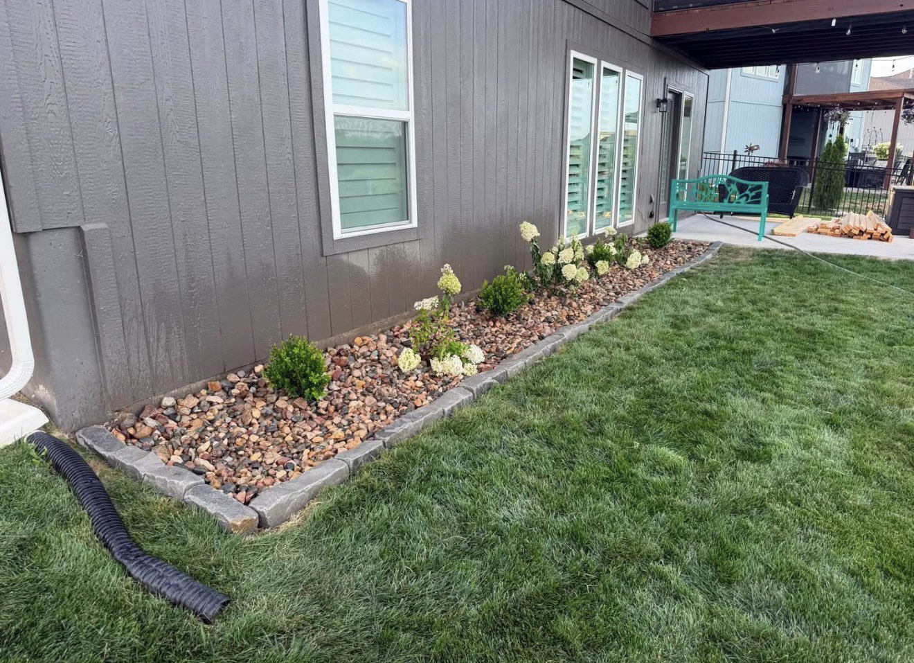 Landscaped rock bed with fresh plantings running along the side of a house